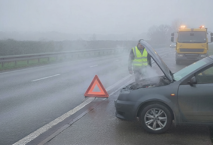 Dépannage en bord de route d'une voiture en panne, dépanneur sur place, personnes en règle avec gilets réfléchissants